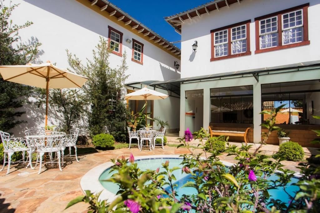 Jardim com piscina e mesas sob guarda-sóis